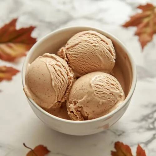 Gros plan sur une glace à la châtaigne, dans un bol, sur un fond de marbre blanc avec des feuilles d'automne