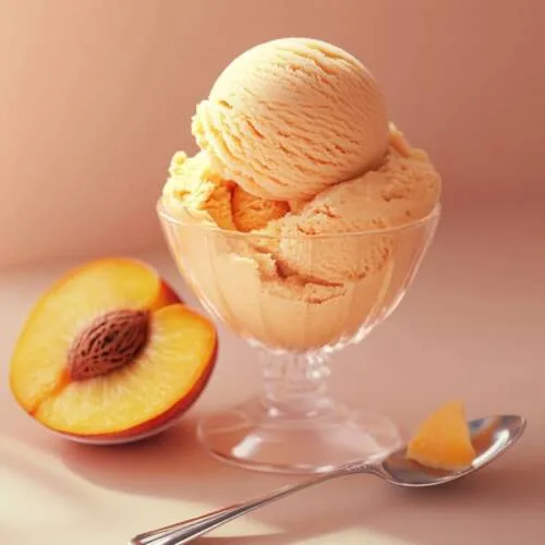 gros plan d'une glace à la pêche dans une coupe en verre, avec une tranche de pêche et une cuillère